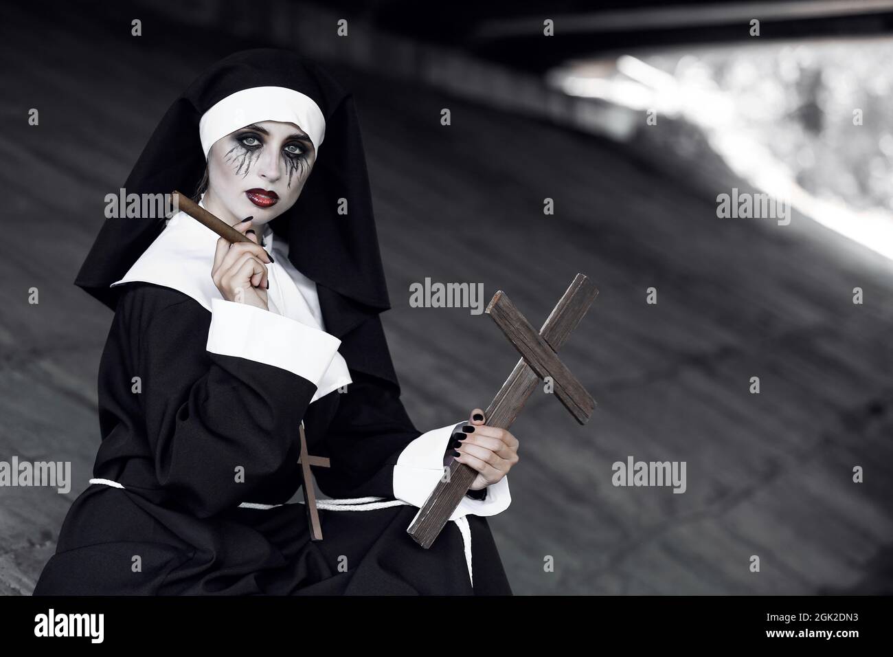 Portrait of woman dressed for Halloween as nun with cigar Stock Photo