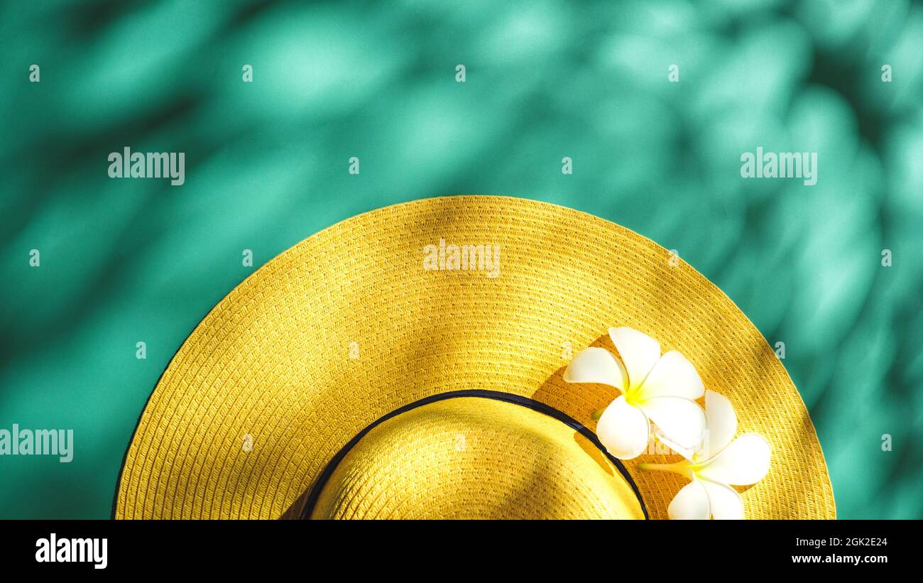 Yellow straw hat over green turquoise background with sunlight ,Minimal summer beach sea Stock Photo