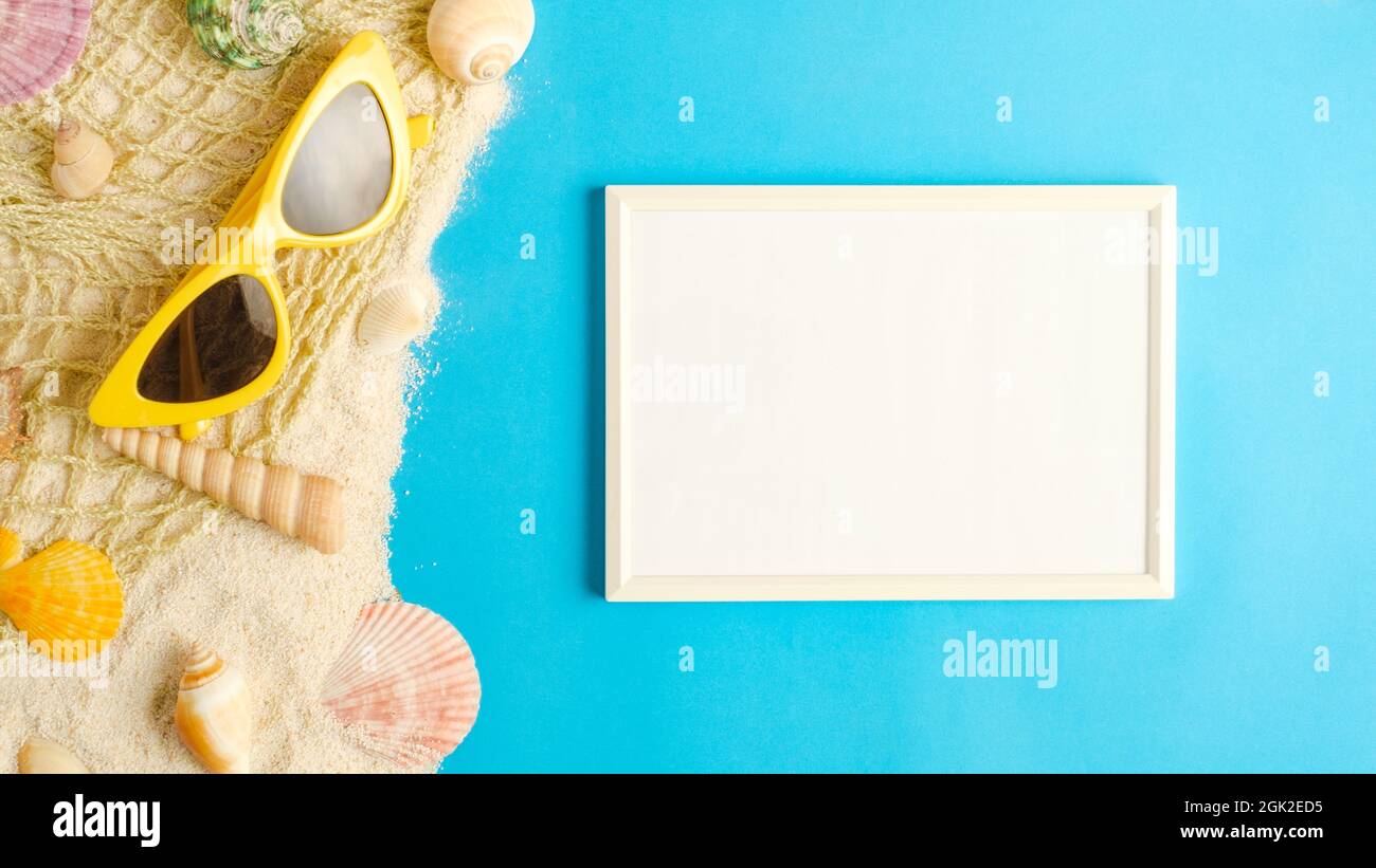 summer sunlight concept.white blank picture frame on sand with beach accessory on blue sea background Stock Photo