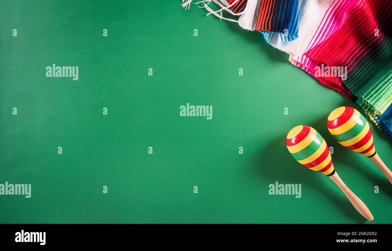 Cinco de Mayo holiday background made from maracas, mexican blanket stripes or poncho serape on green background. Stock Photo