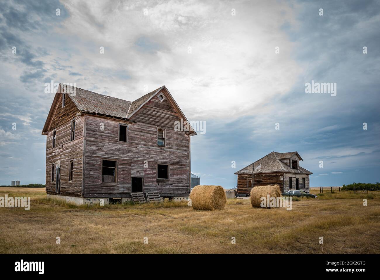 Two abandoned homes, hay bales and a classic car in the ghost town of