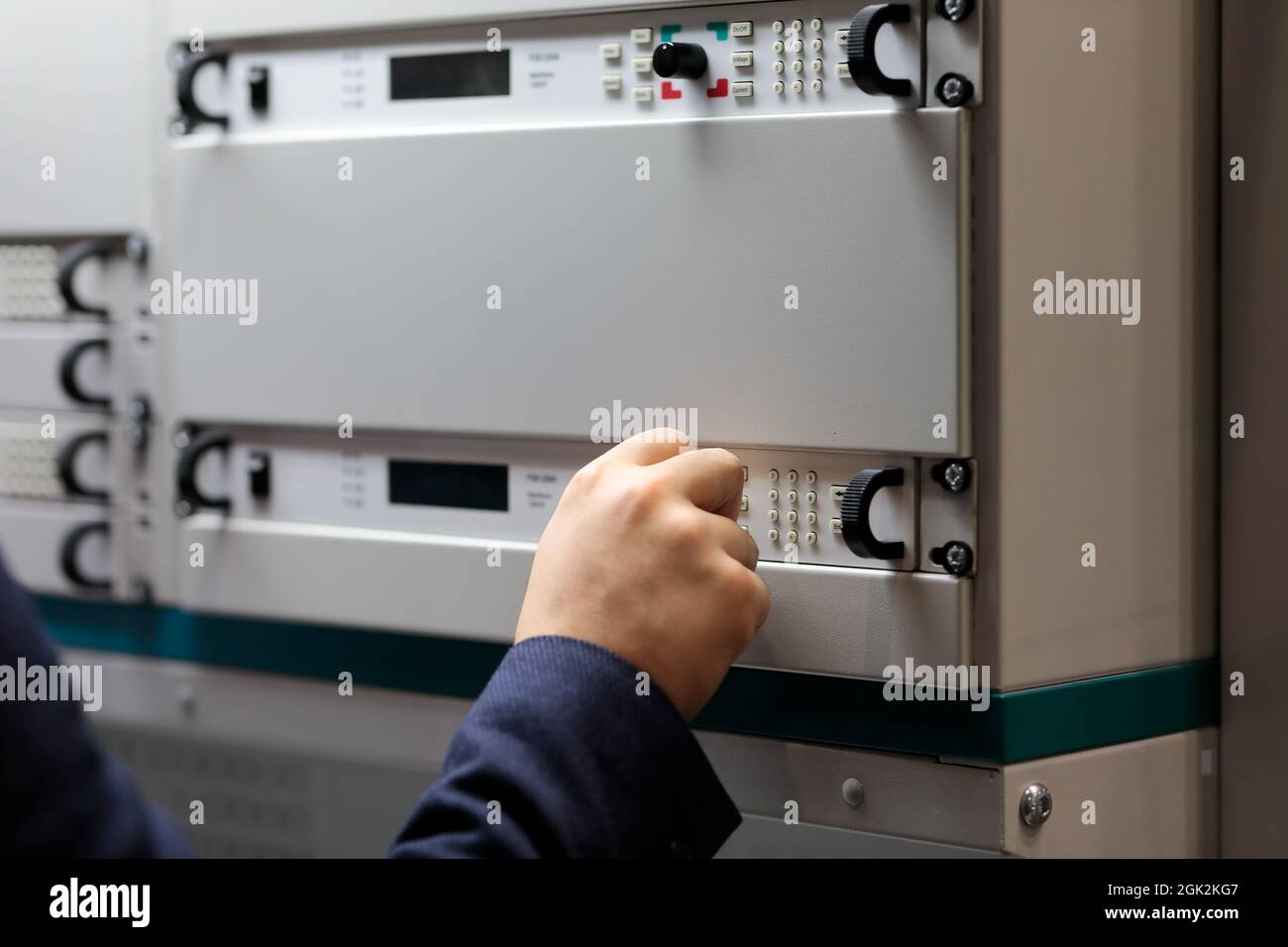Engineer controls industrial digital equipment mounted in a rack. Selective focus. Stock Photo