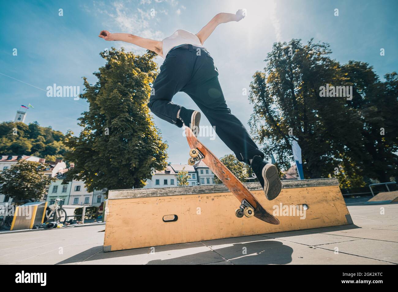 Anonymous skateboarder performing a trick on a wooden box on a sunny day in the city center. Young skater jumping. Stock Photo