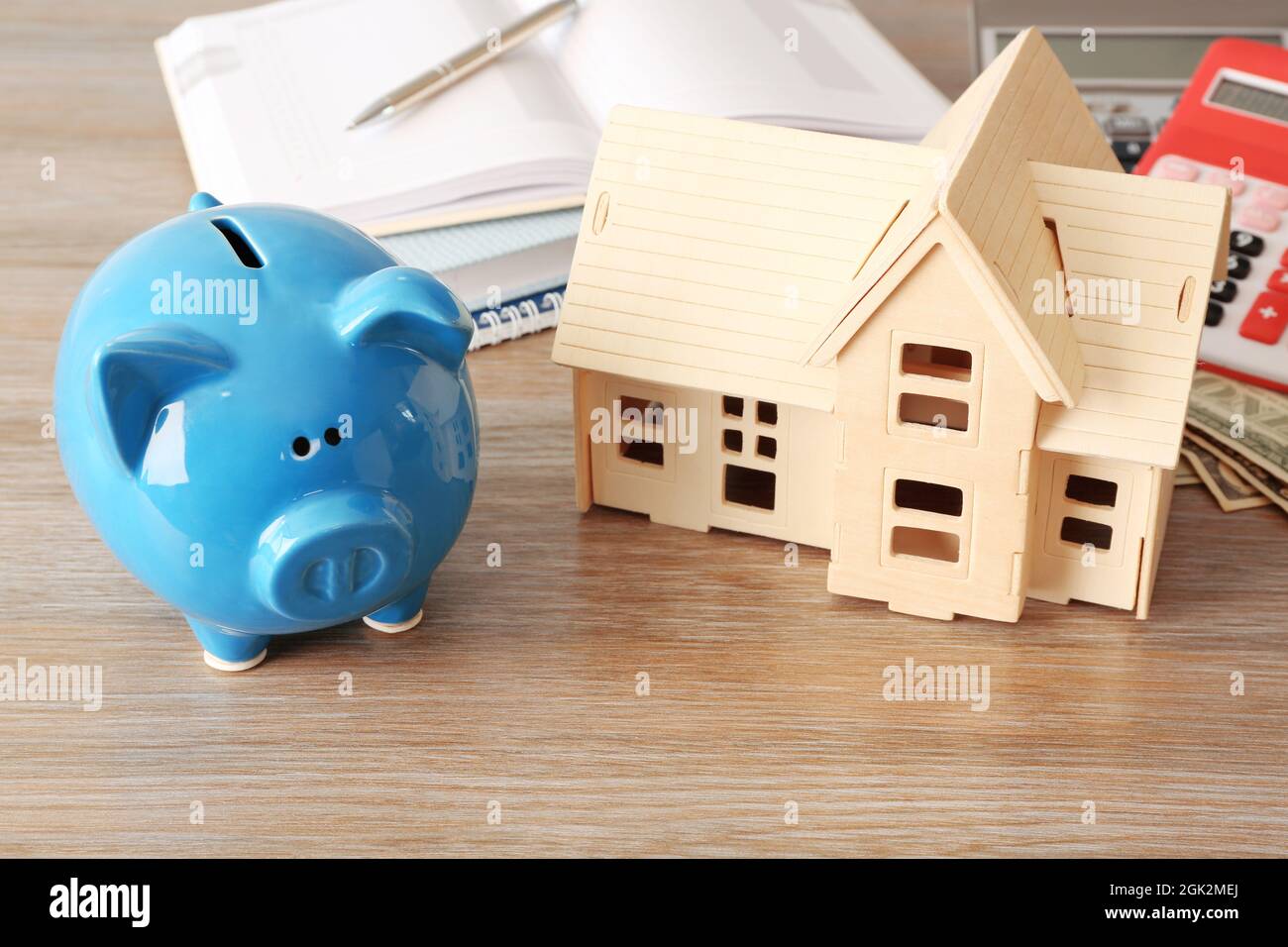 Piggy bank, stationery and house model on table. Savings concept Stock ...