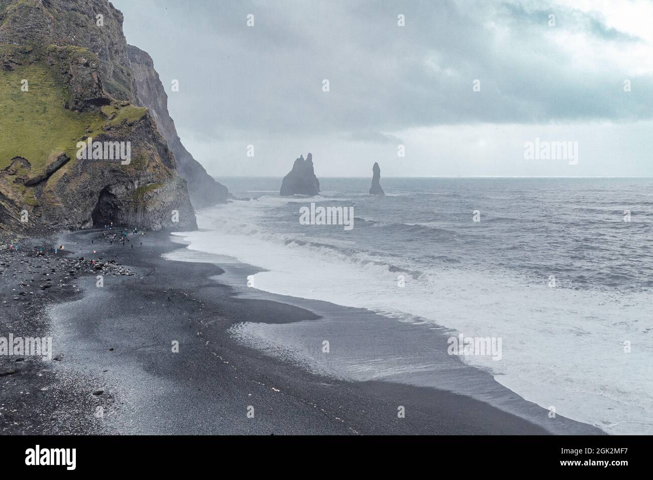Aerial drone view of Reynisfjara beach in Iceland with big basalt pillars and rocky beach. Cold windi place at the beach with big waves. Stock Photo