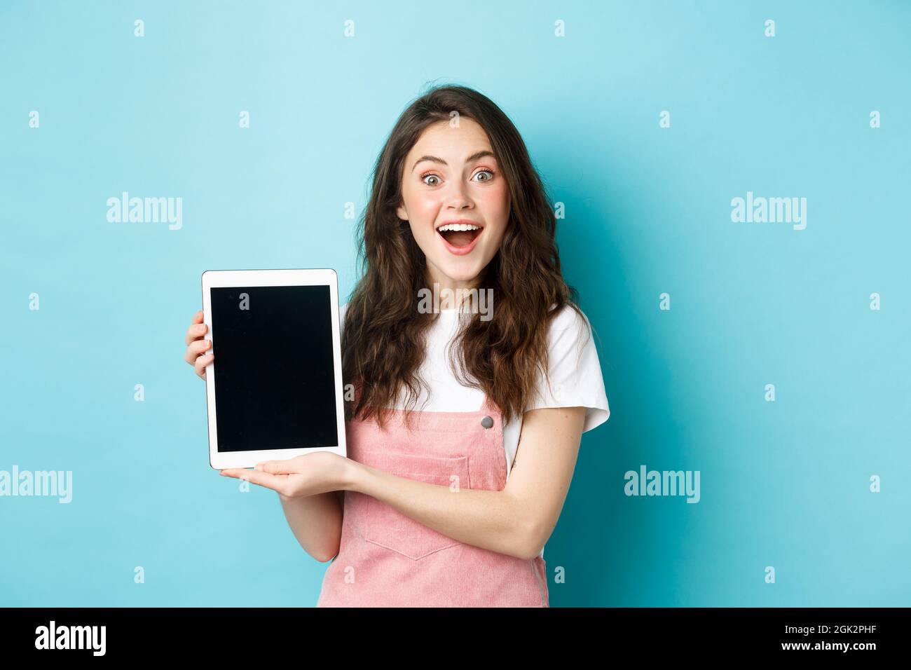 Amused pretty girl demonstrate blank digital tablet screen and smiling ...
