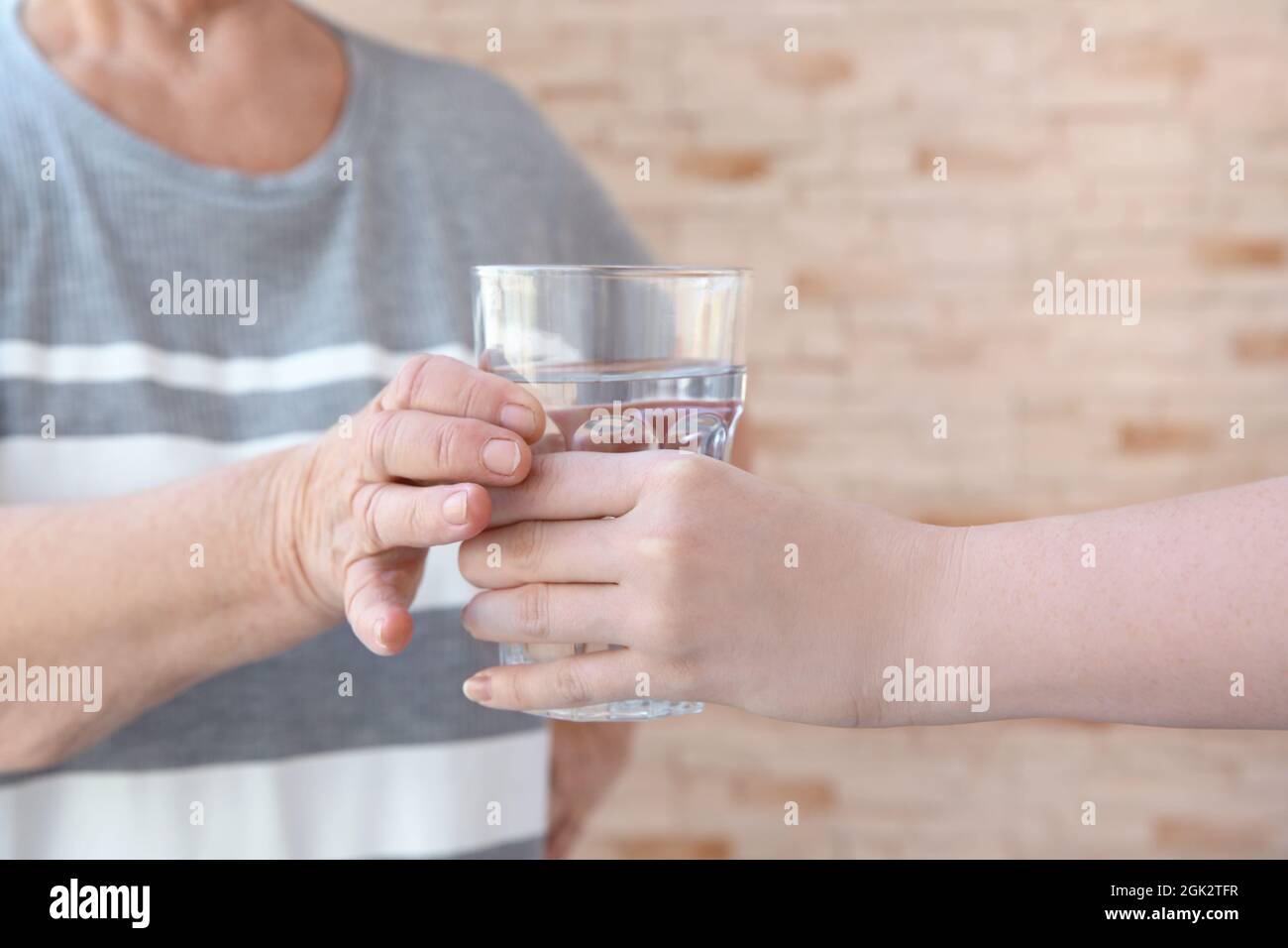 Young lady giving glass of water to elderly woman. Concept of nursing Stock Photo