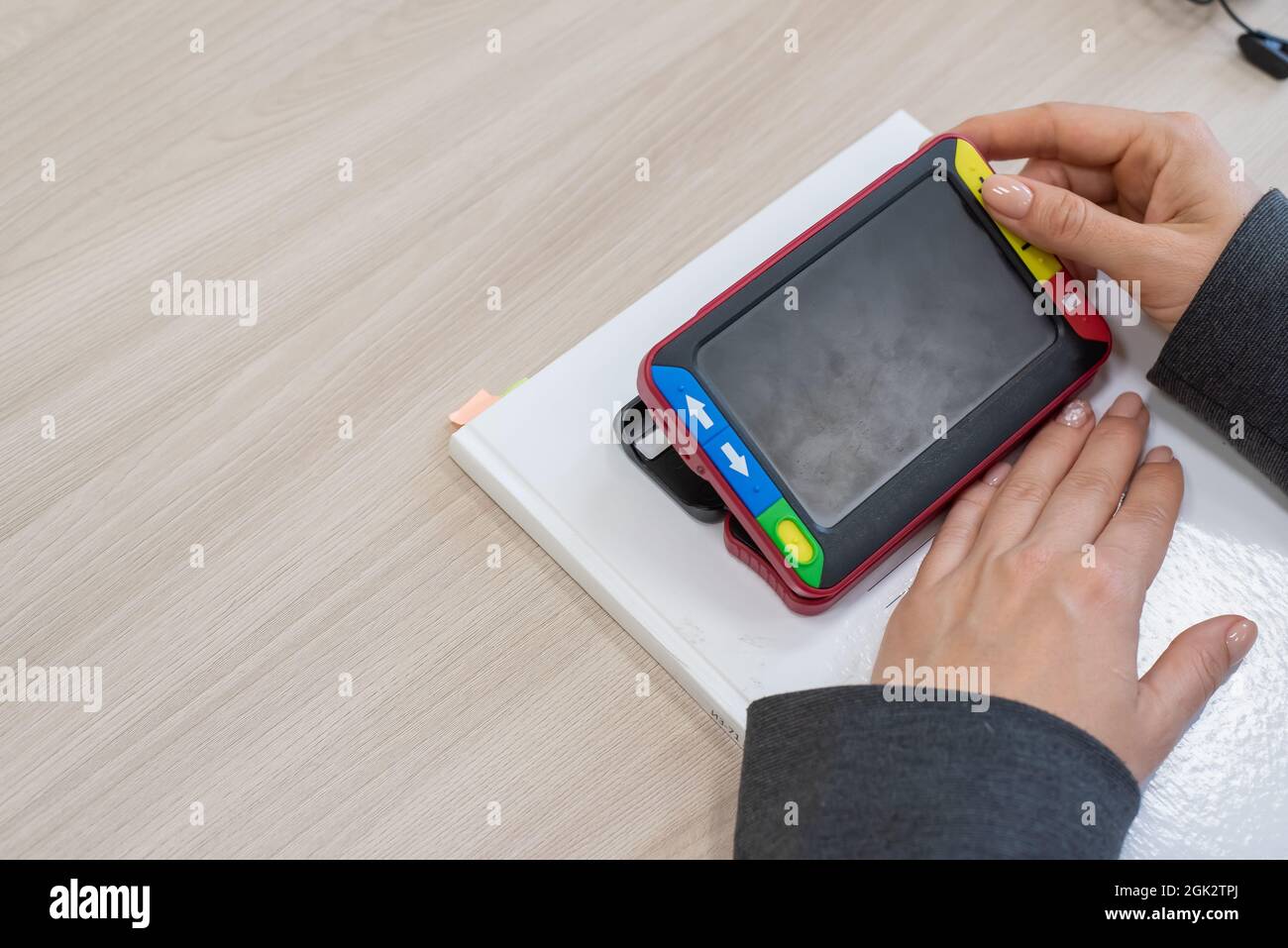 The woman is holding a reading device for the visually impaired