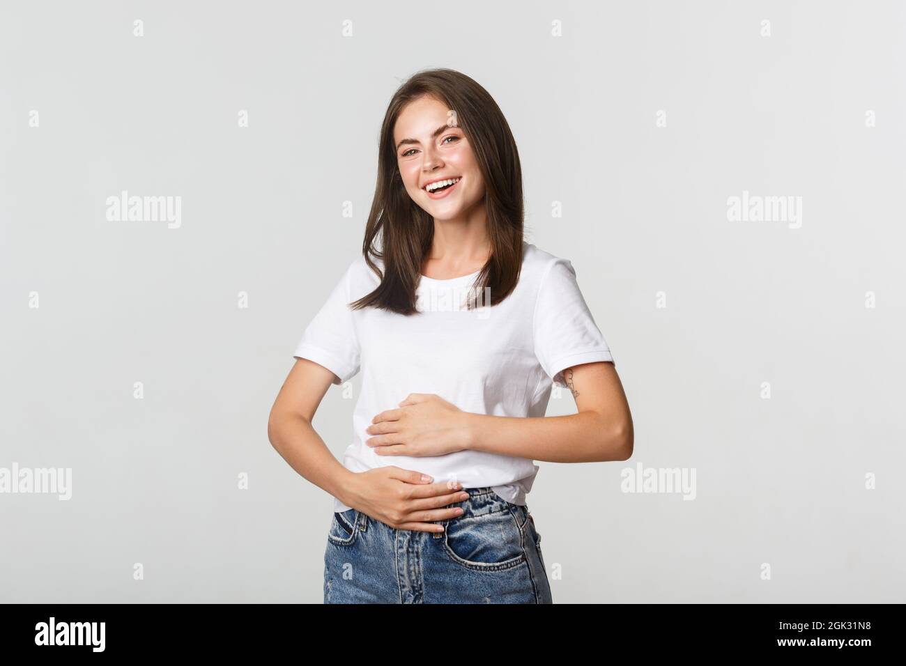 Satisfied smiling girl rubbing belly after eating delicious