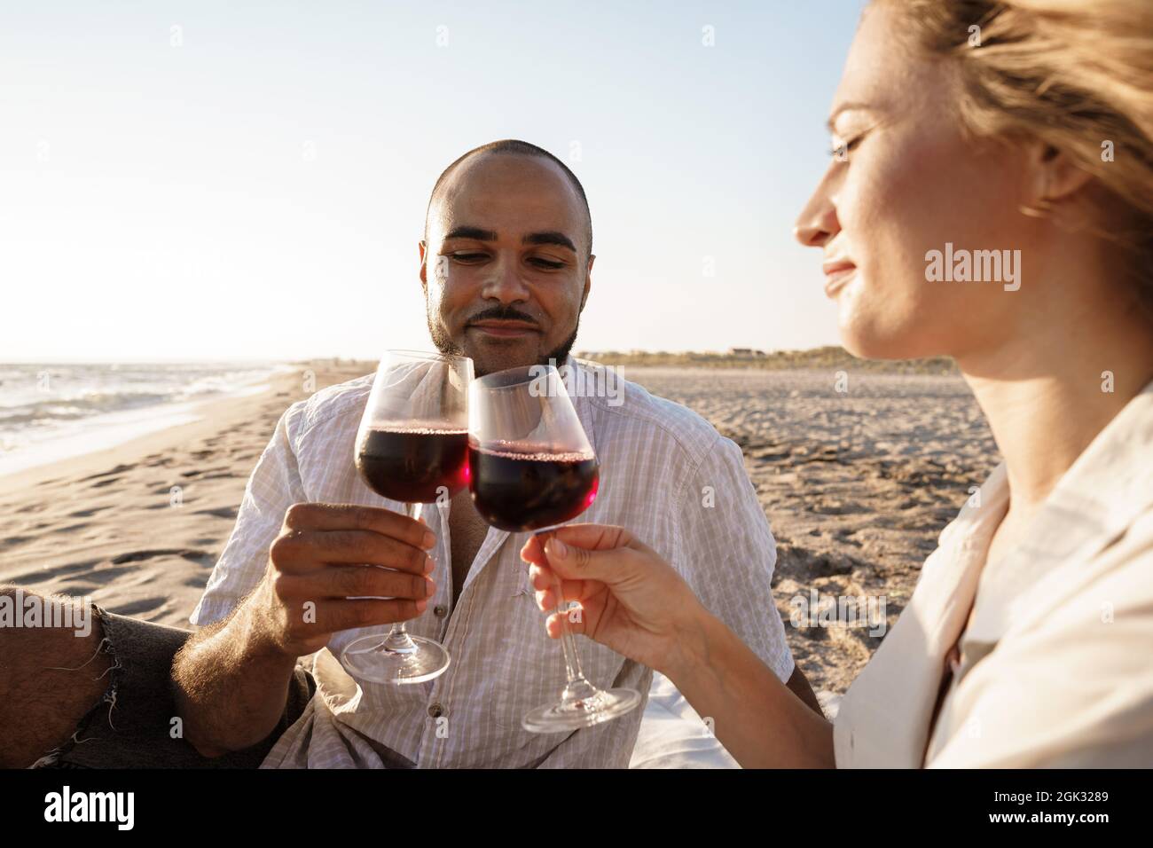 Portrait of a young couple sitting on the beach and drinking wine Stock ...