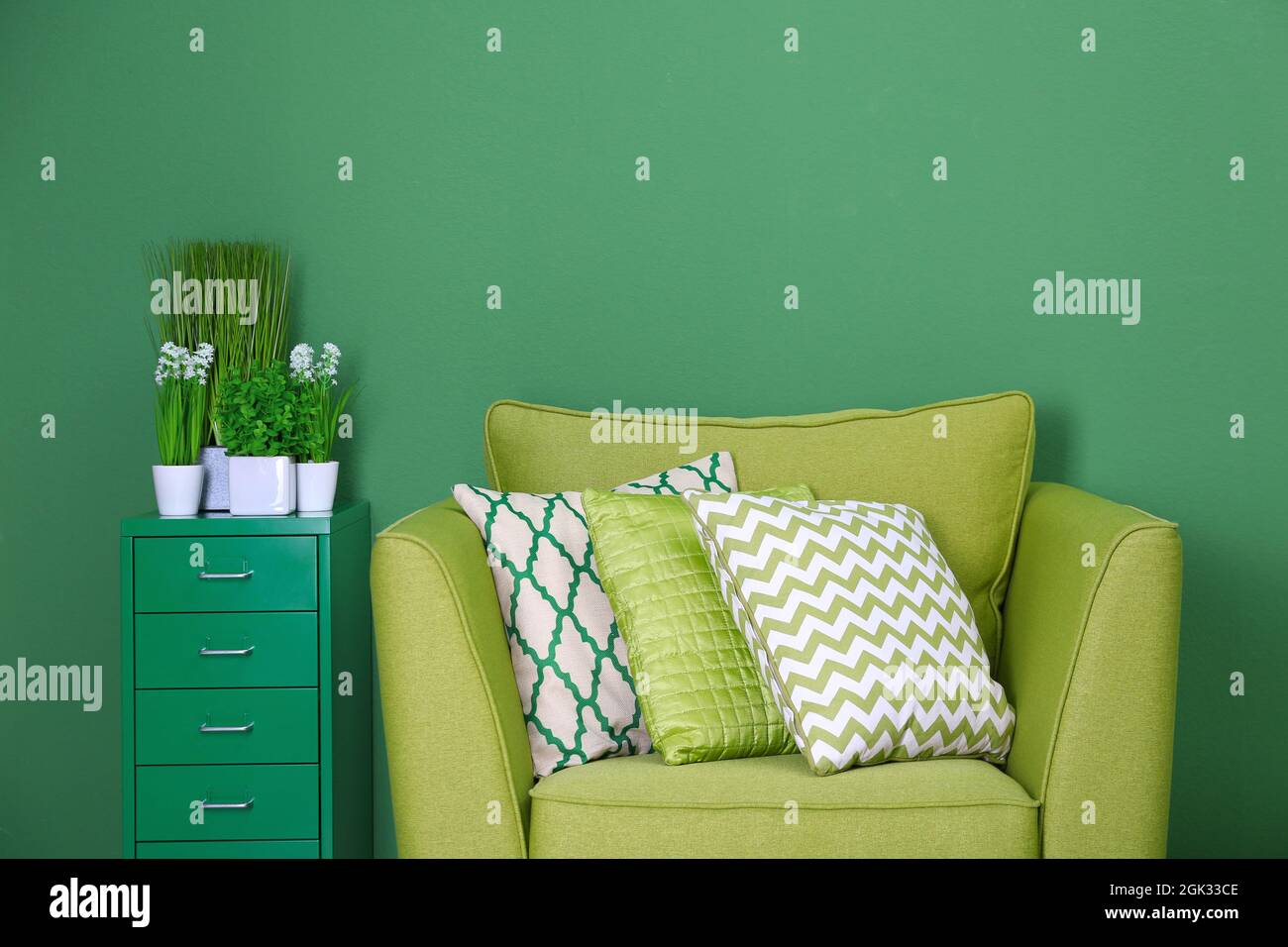 Cozy armchair with pillows on green background Stock Photo - Alamy