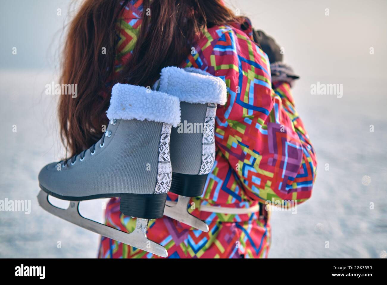 A woman in a ski suit holds skates on her shoulder, after skiing on a frozen lake, closeup Stock Photo