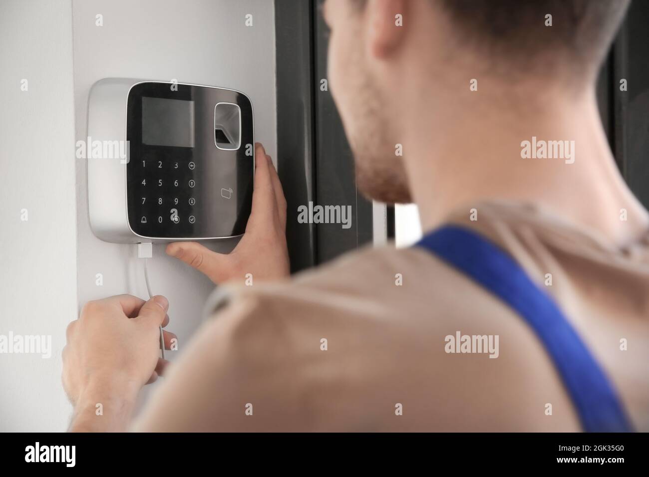 Young electrician installing security alarm on wall Stock Photo Alamy