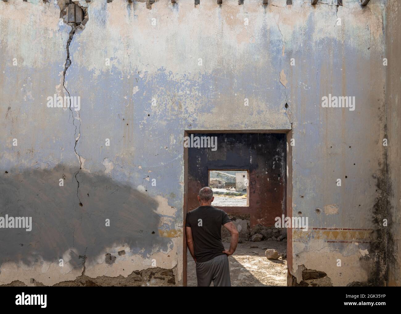 Rear view of adult man standing in doorway of an abandoned house Stock Photo
