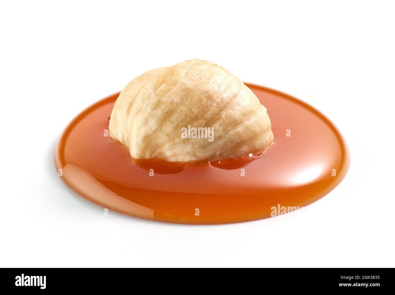 hazelnut in melted caramel drop isolatedd on white background Stock