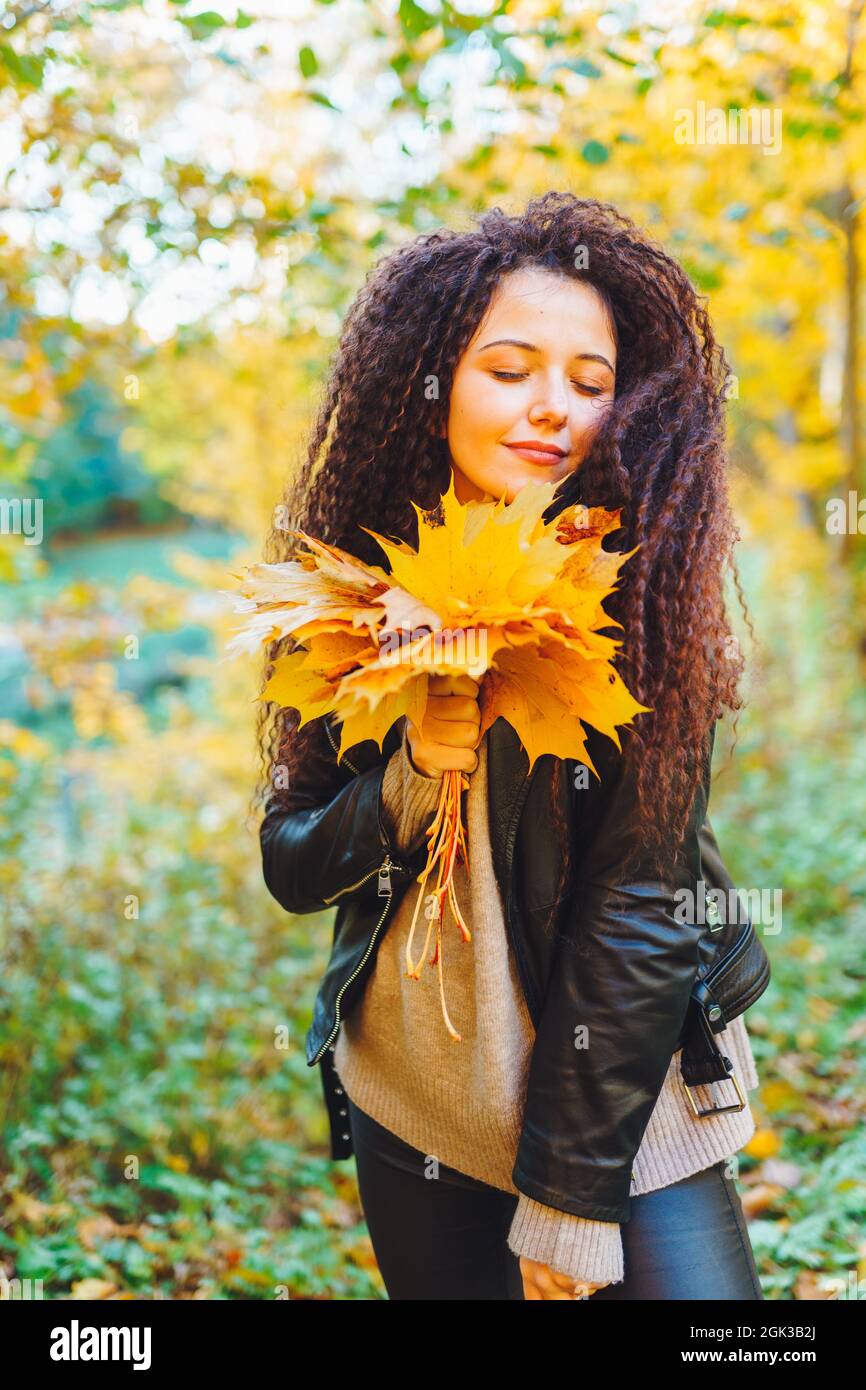 Young beautiful woman with a bouquet of yellow autumn leaves in the ...
