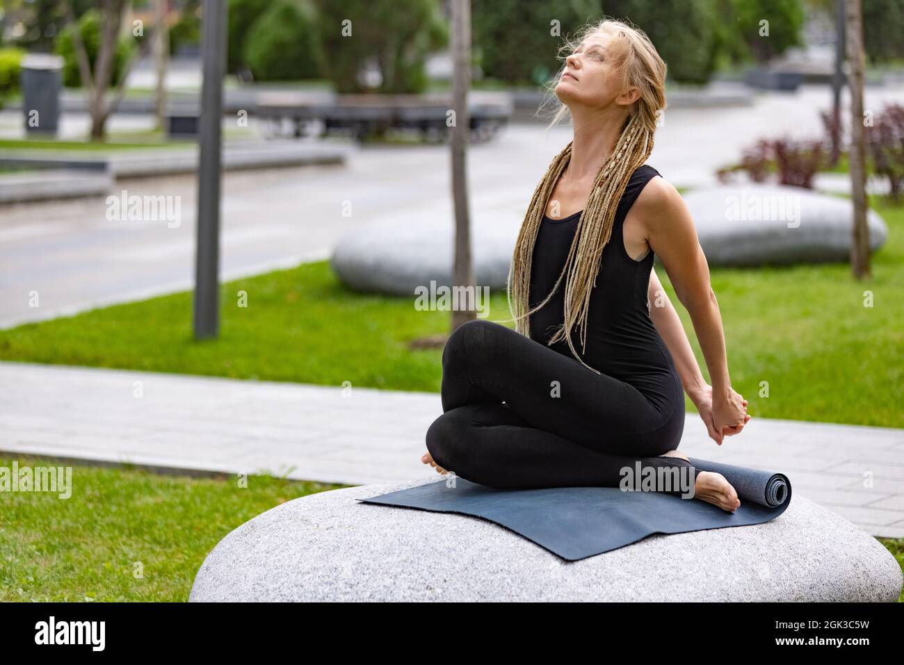 Young beautiful woman with blonde hair doing yoga exercise in green public  park in summer morning, outdoors. Healthy lifestyle, mental health concept  Stock Photo - Alamy