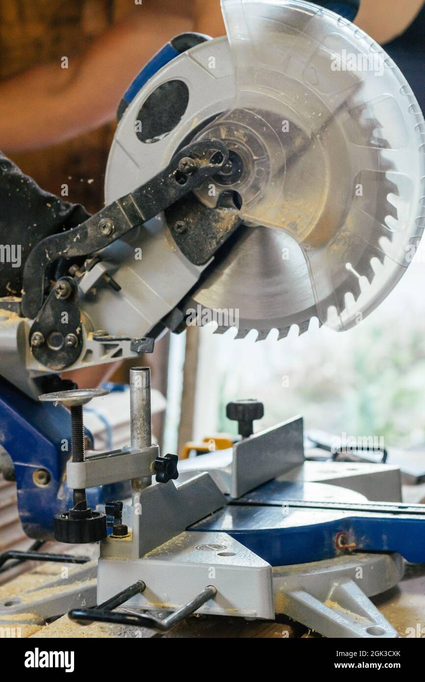 Professional miter saw standing on stack of boards with trim planks for