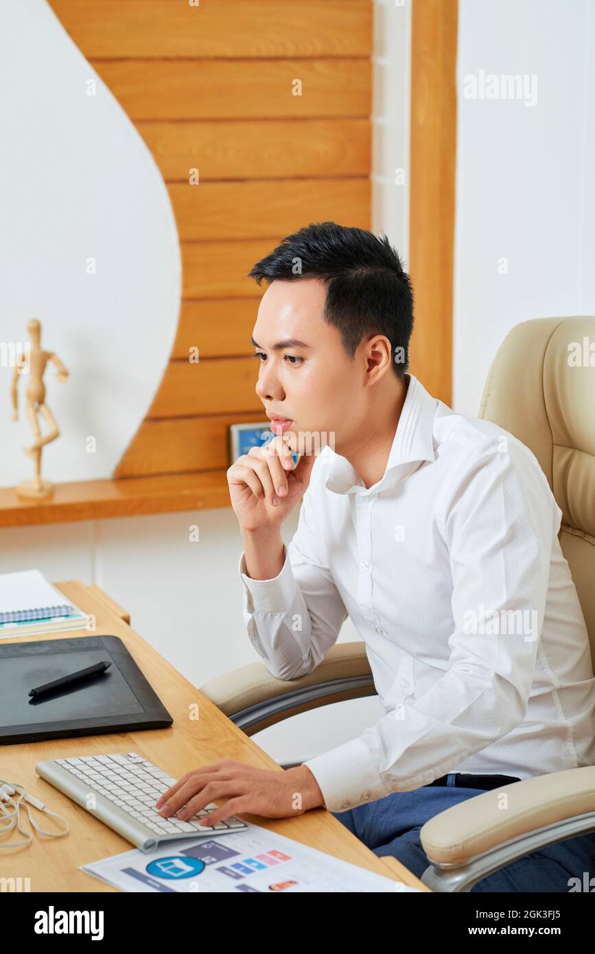 Pensive young graphic designer reading e-mail from customer containing requirement specification Stock Photo