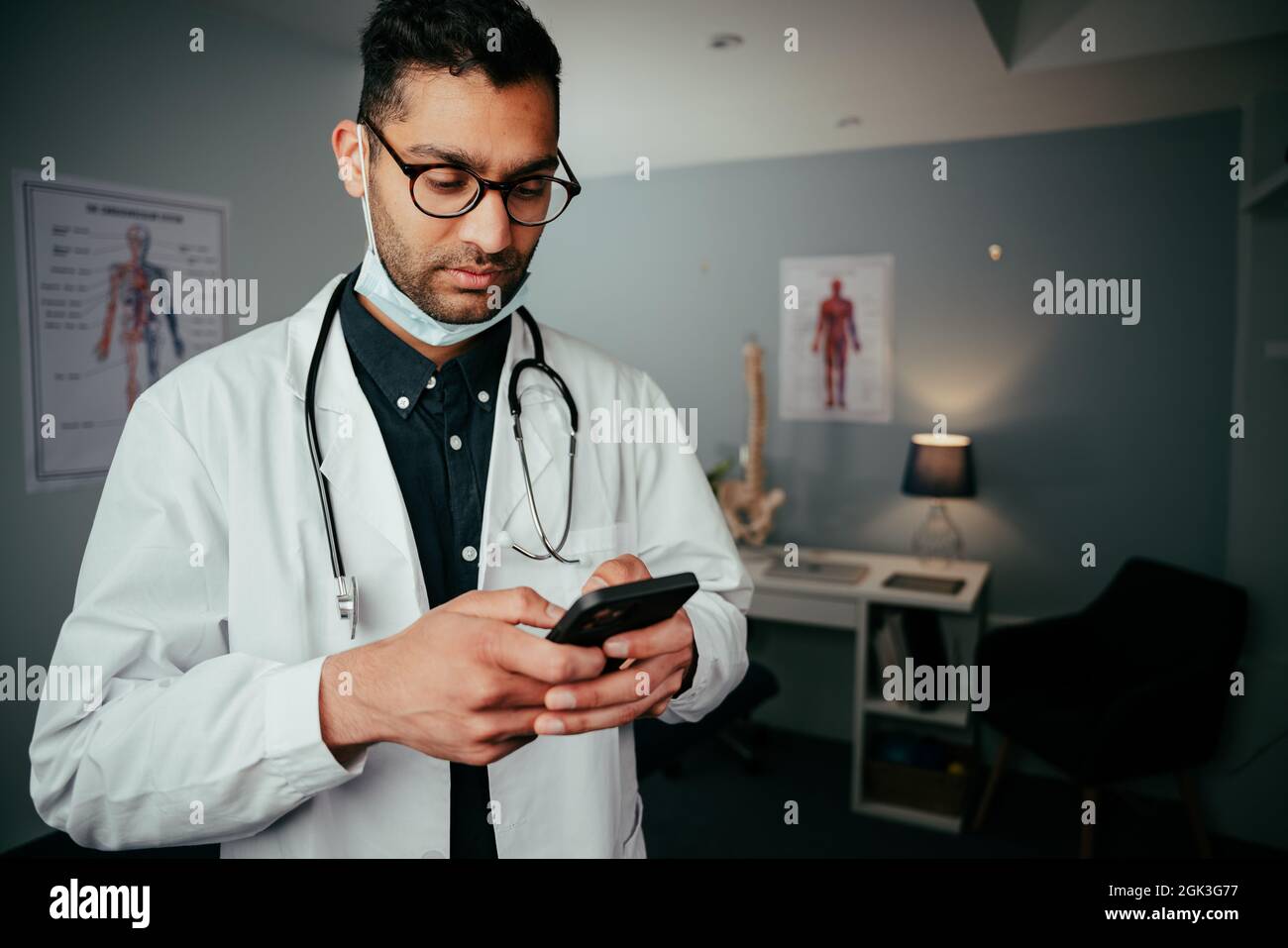 Mixed race male nurse texting on cellular device standing in clinic Stock Photo