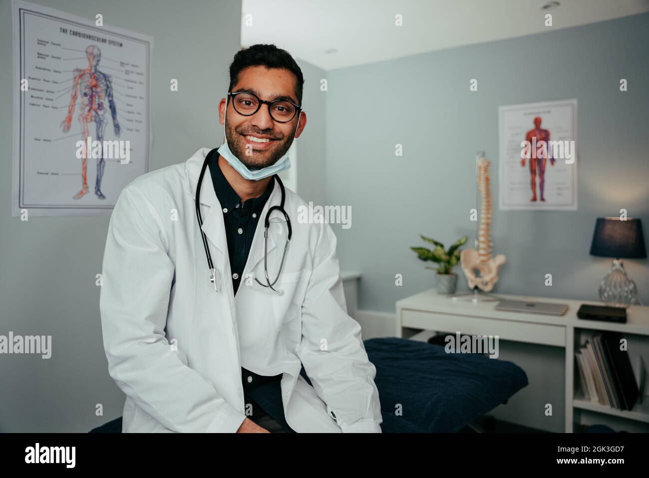Smiling mixed race male doctor working from office wearing lab coat Stock Photo