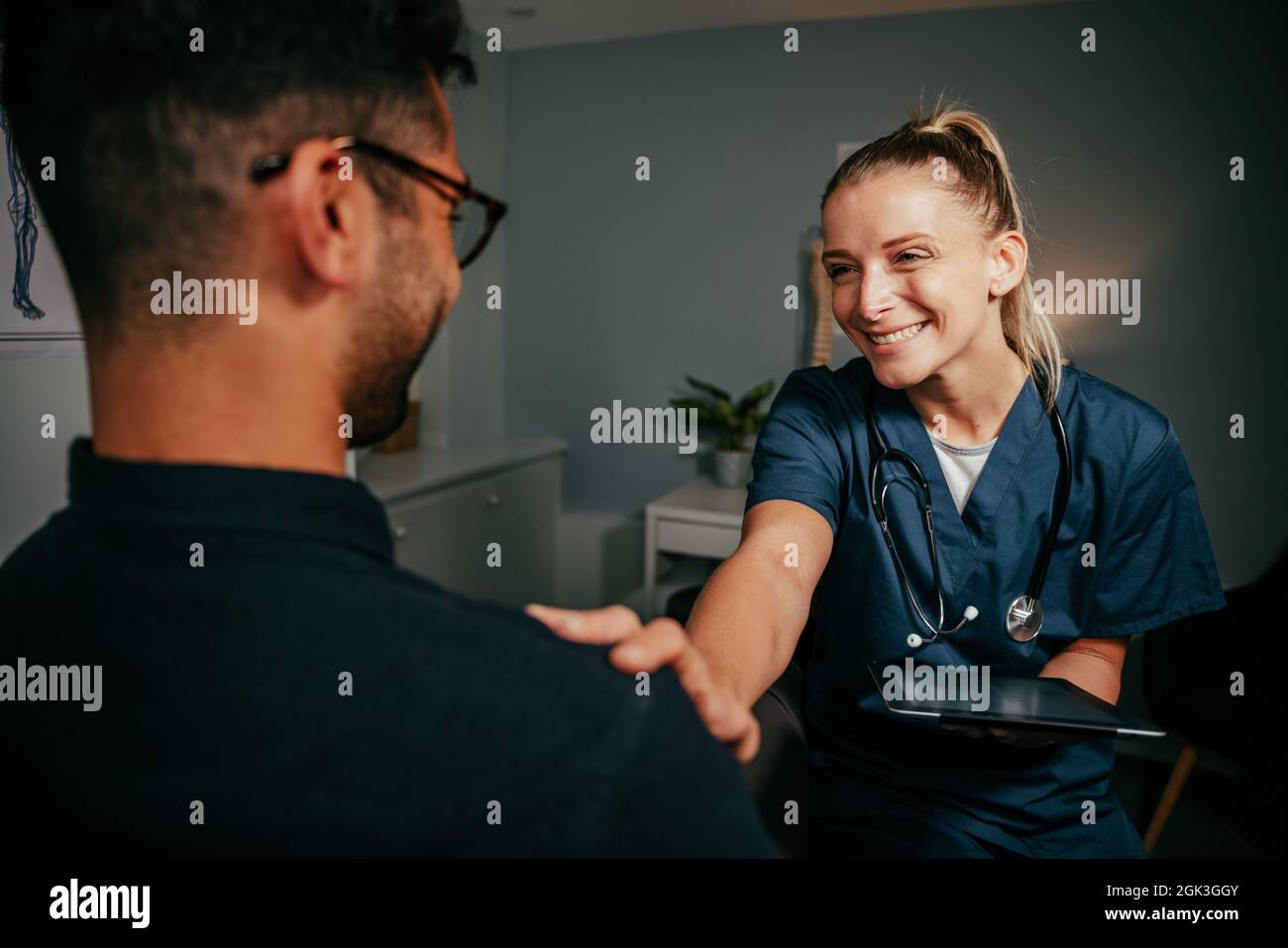 Mixed race female nurse chatting to male patient Stock Photo