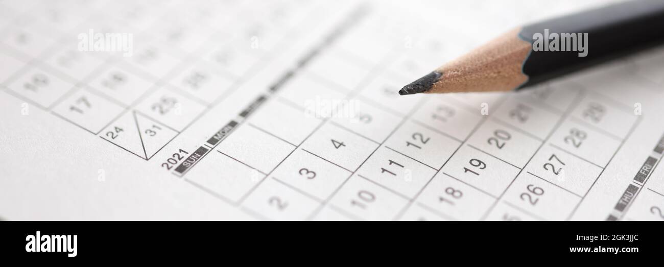 Black pencil lies on calendar with dates Stock Photo