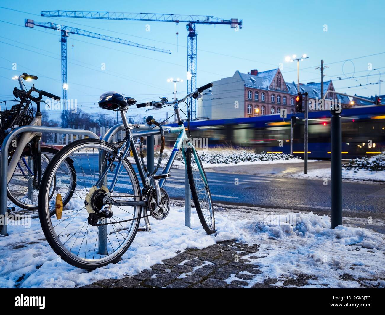 old bicycle parked on a rack in a winter city, urban environment with construction site on background Stock Photo