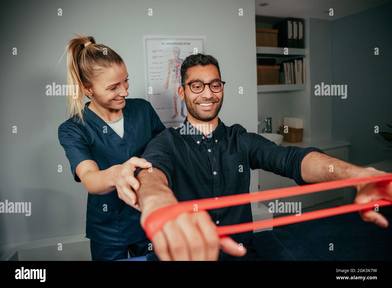 Caucasian female physiotherapist assisting male patient holding resistance band Stock Photo