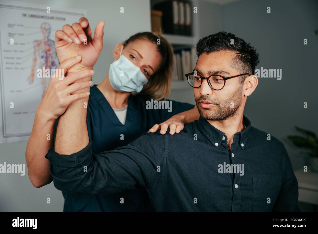Caucasian female nurse adjusting arm of male patient in clinic Stock Photo