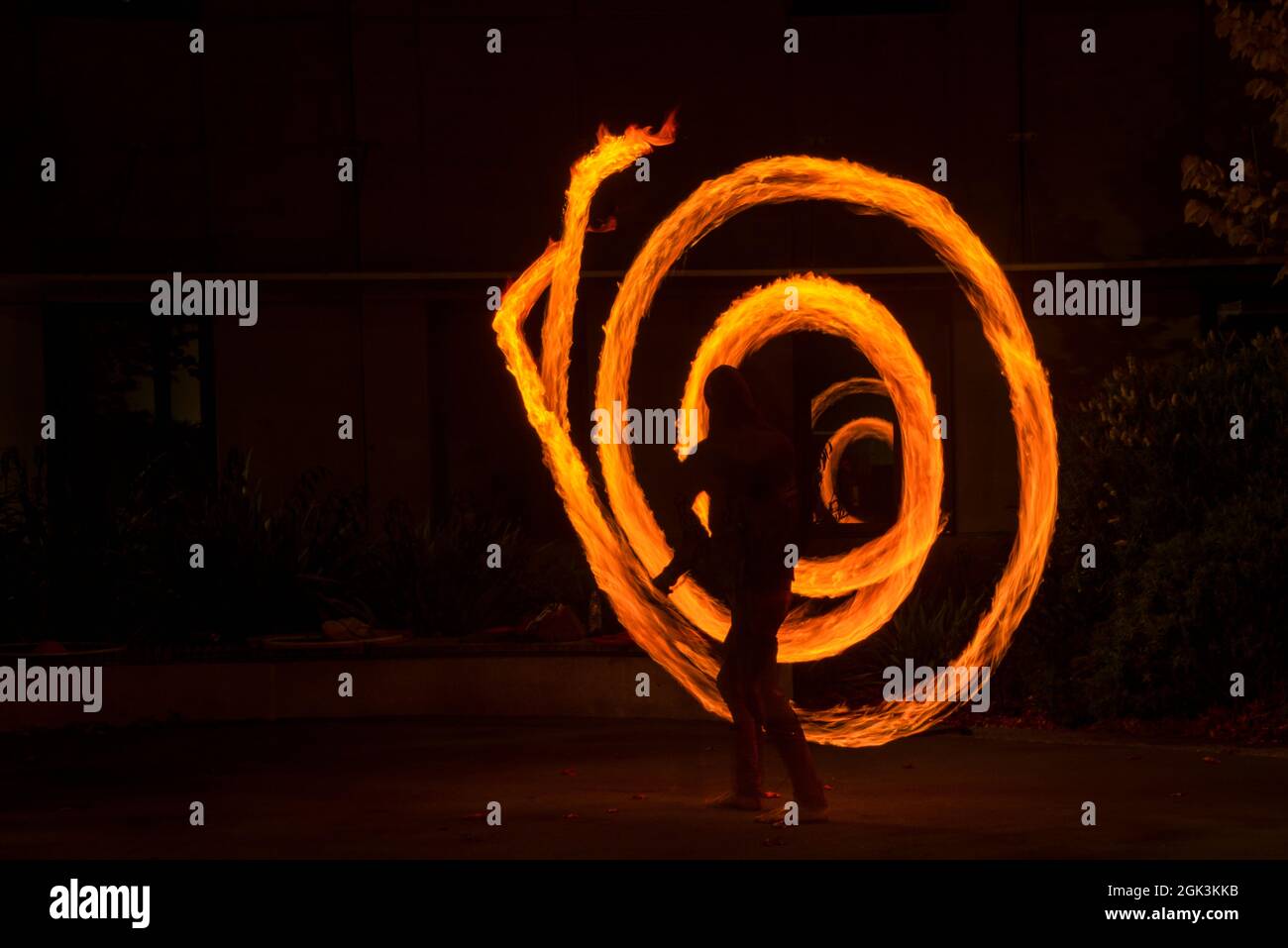 Street artist juggling with burning poi at fire performance. Long