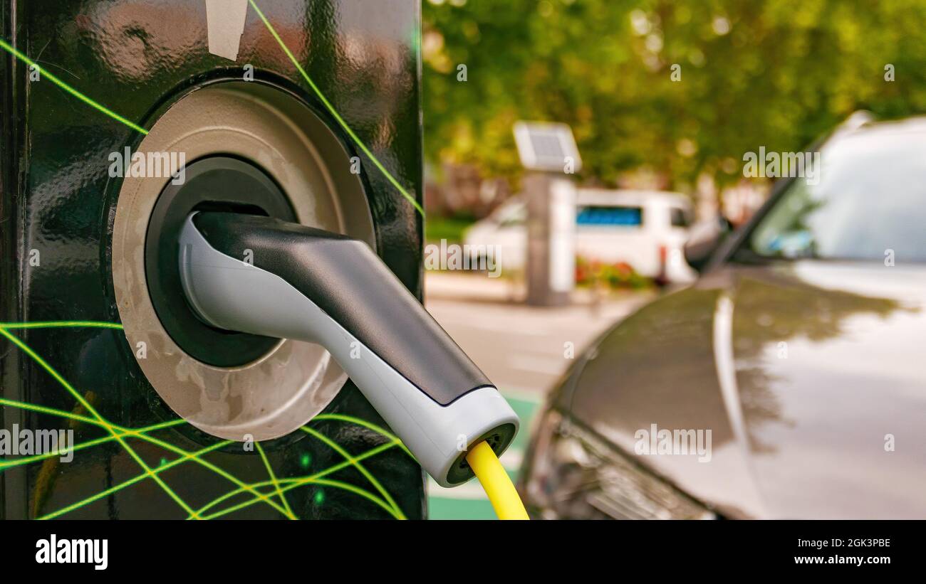 Electric car plugged at charging station to fill the battery, close up ...