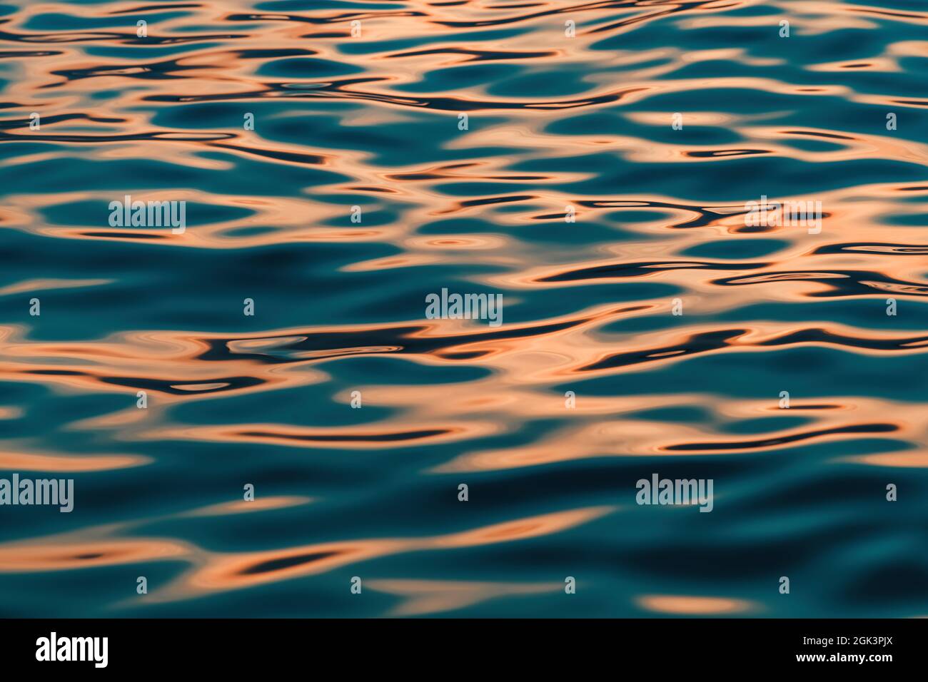 Rippled surface of blue sea water in sunset, orange and teal tones, selective focus Stock Photo