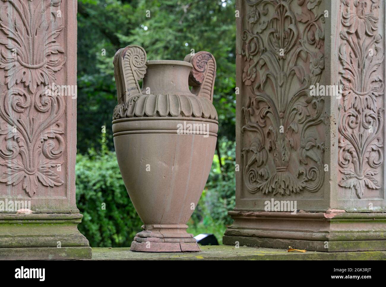 Antique-styled stone vase surrounded by decorative stone plates in a cemetery Stock Photo