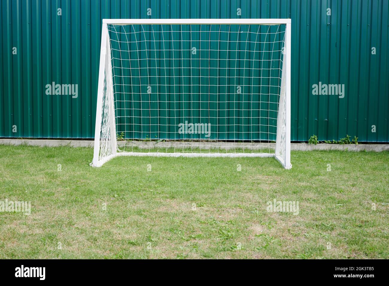 Empty sport white gate on green grass field in kid playground Stock Photo