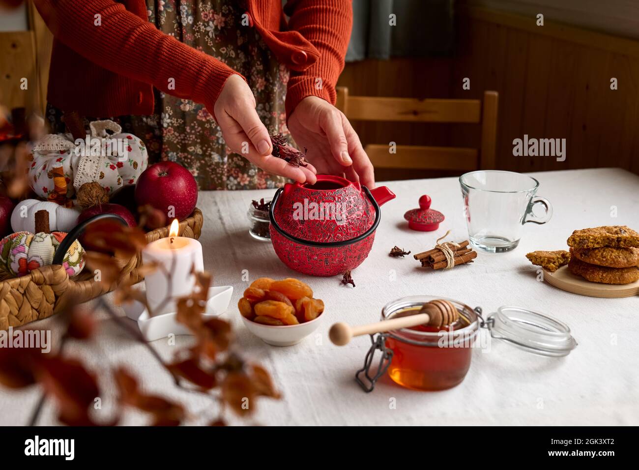 Cozy autumn days. Woman wearing orange sweater brew tea in red teapot on the table with linen tablecloth. Aromatic mood. Fall vibes. Tea drinking.Than Stock Photo