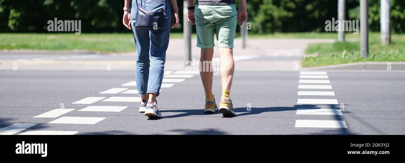 Man and woman cross the road at pedestrian crossing Stock Photo - Alamy
