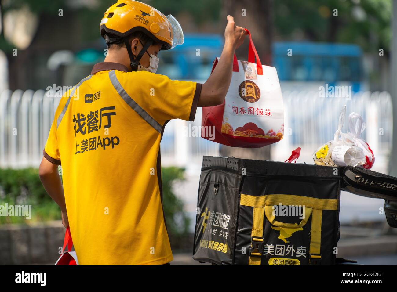 A Meituan courier picks up food from a restaurant and loads it on an electric scooter in Beijing, China. 13-Sep-2021 Stock Photo