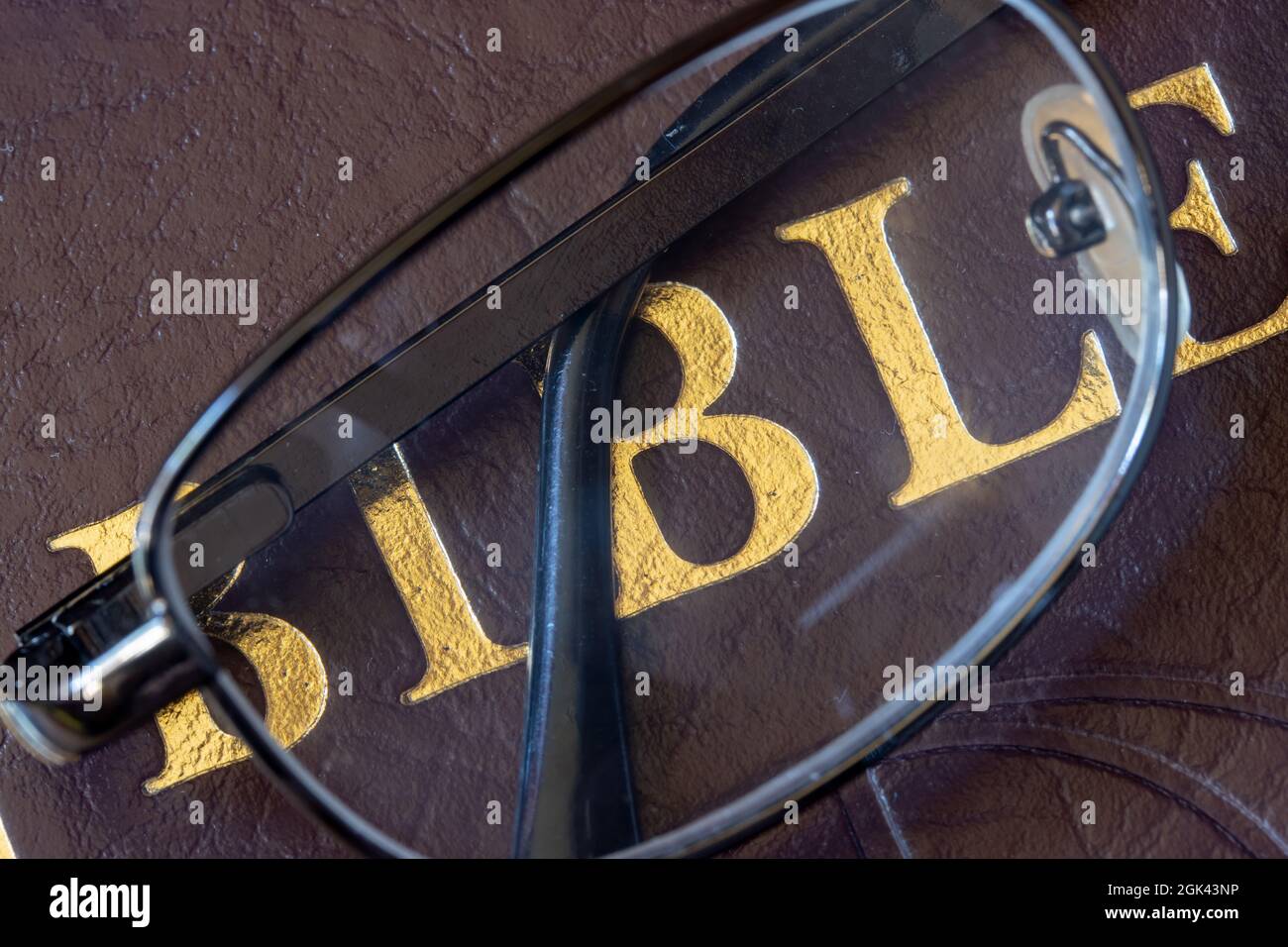 A reading glasses lying on the cover of the Bible, close up. Stock Photo