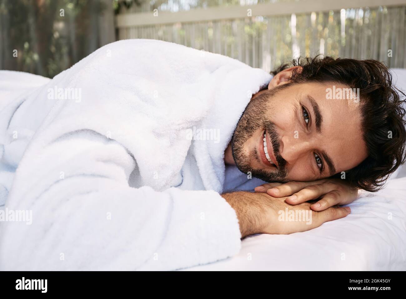 Handsome man wearing a white bathrobe enjoying relaxation at wellness center. Spa for men Stock Photo
