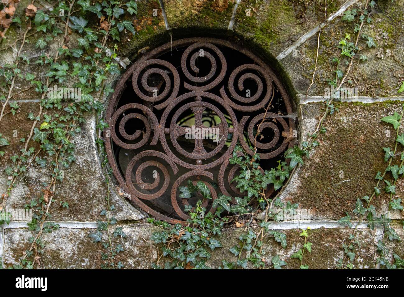 A Round window with bars in a historic stone tomb. Stock Photo