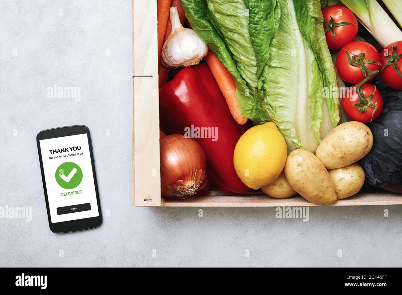 Fresh food delivery service concept. Top view of a smartphone and wooden box full of fresh