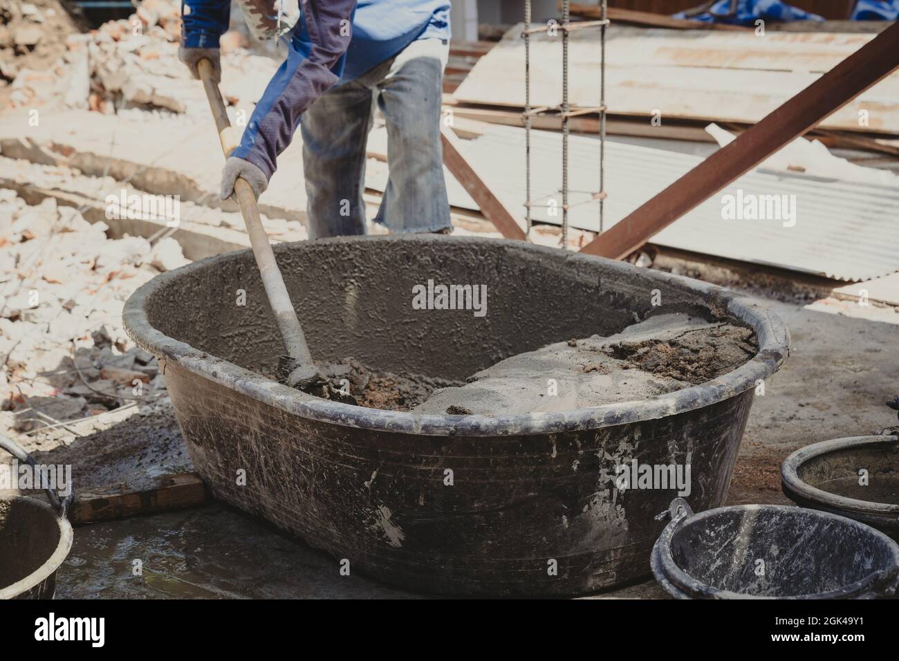 Worker man house builder mix mortar from a trough in bucket Stock Photo