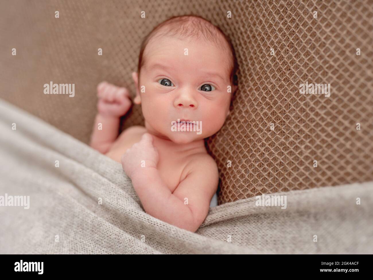 Cute sleepless newborn in funny hat looking to side Stock Photo