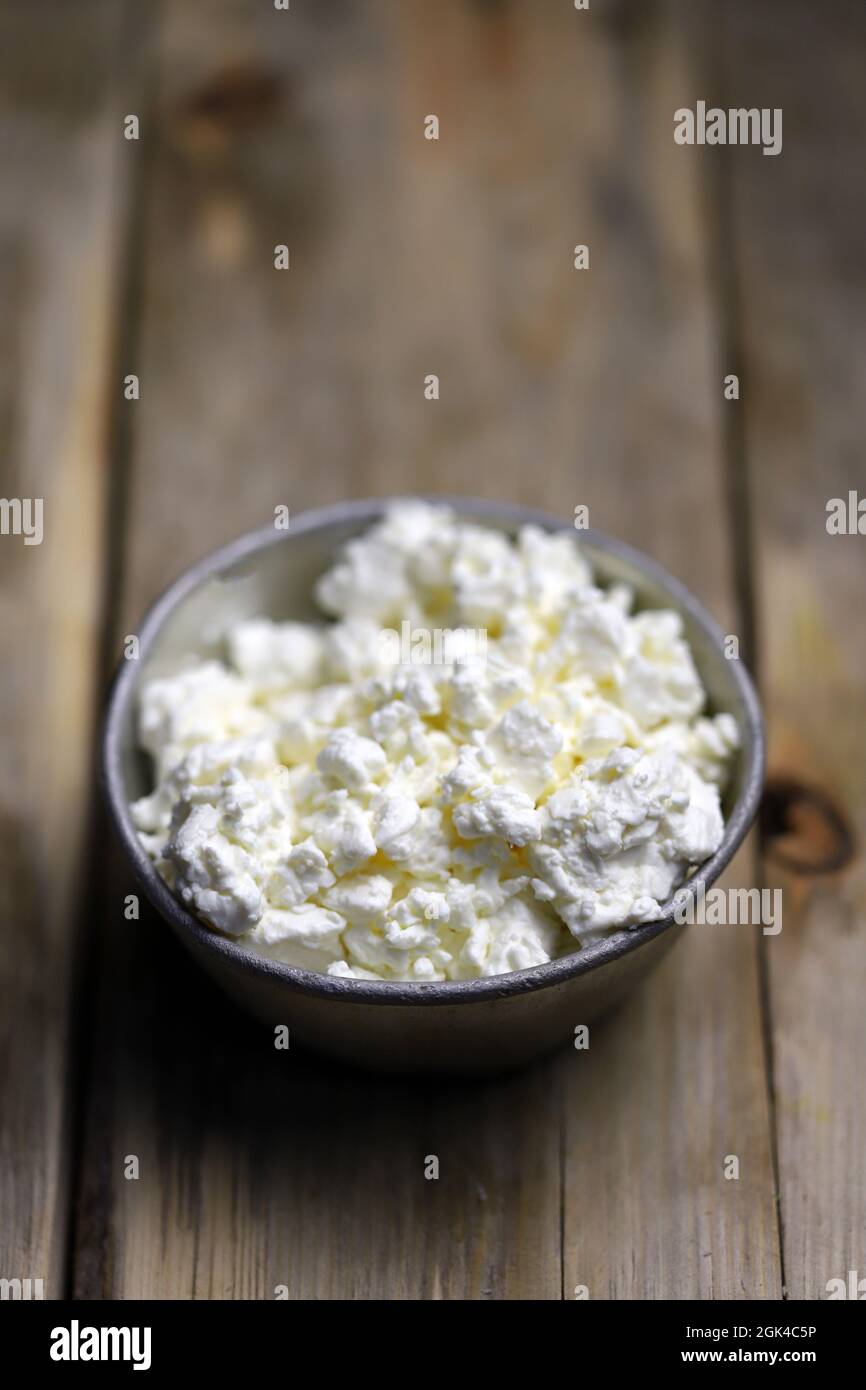 Fresh cottage cheese in an iron bowl. Rustic style. Stock Photo