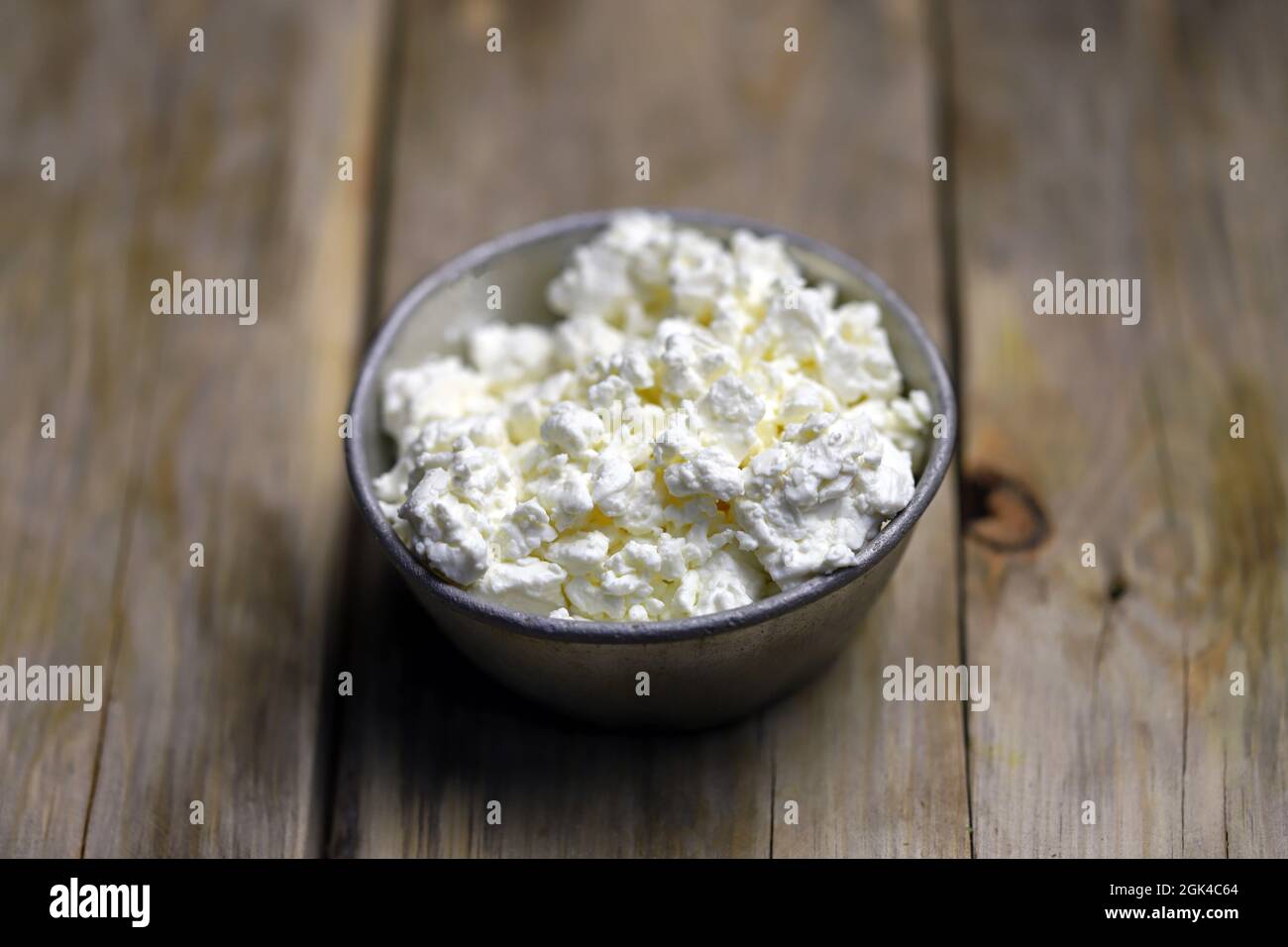 Fresh cottage cheese in an iron bowl. Rustic style. Stock Photo