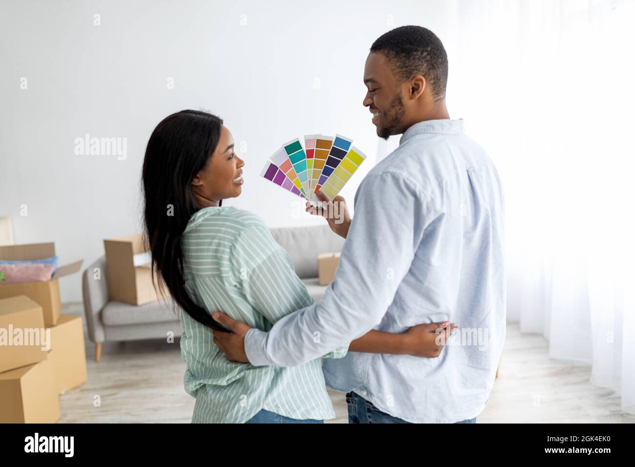 African american spouses choosing color for walls painting, holding palette, standing back to camera at home Stock Photo
