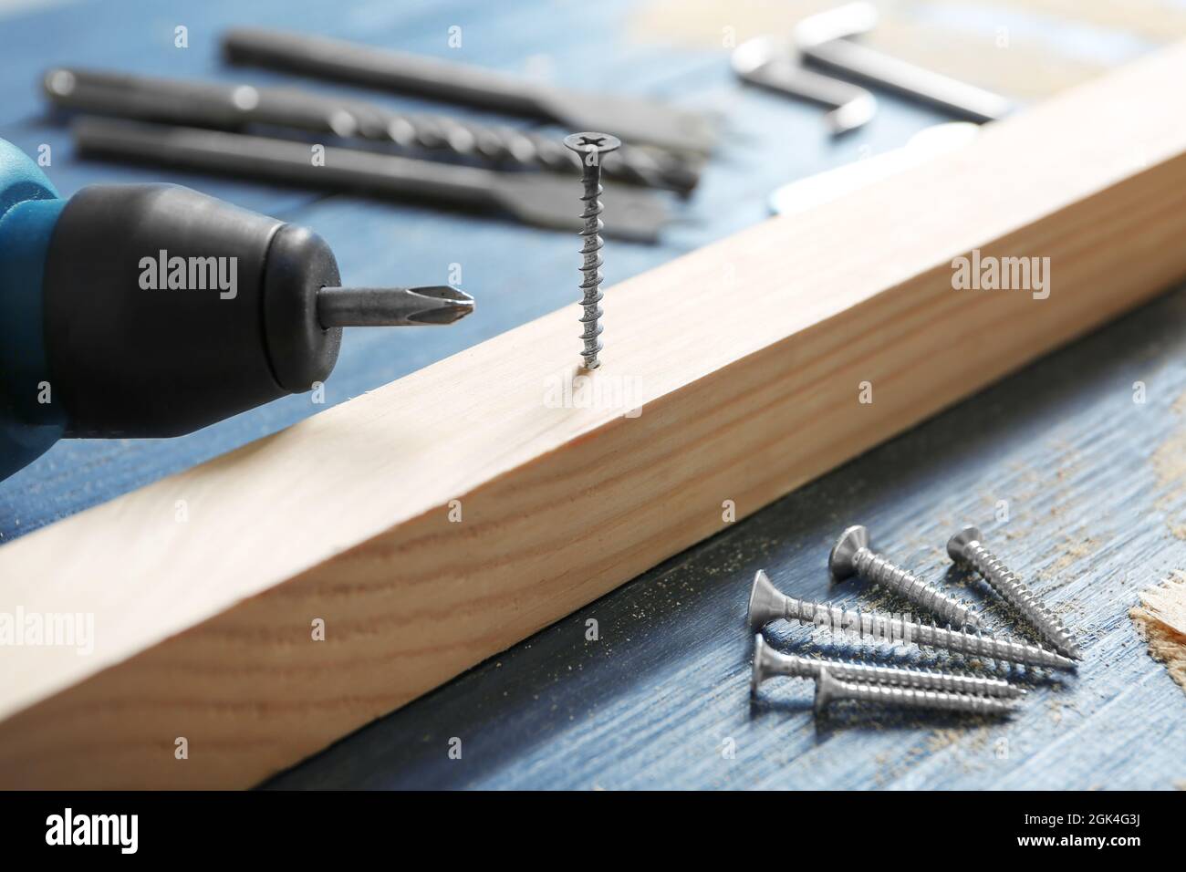 Wooden bar, screw nails and drill on table in carpenter's