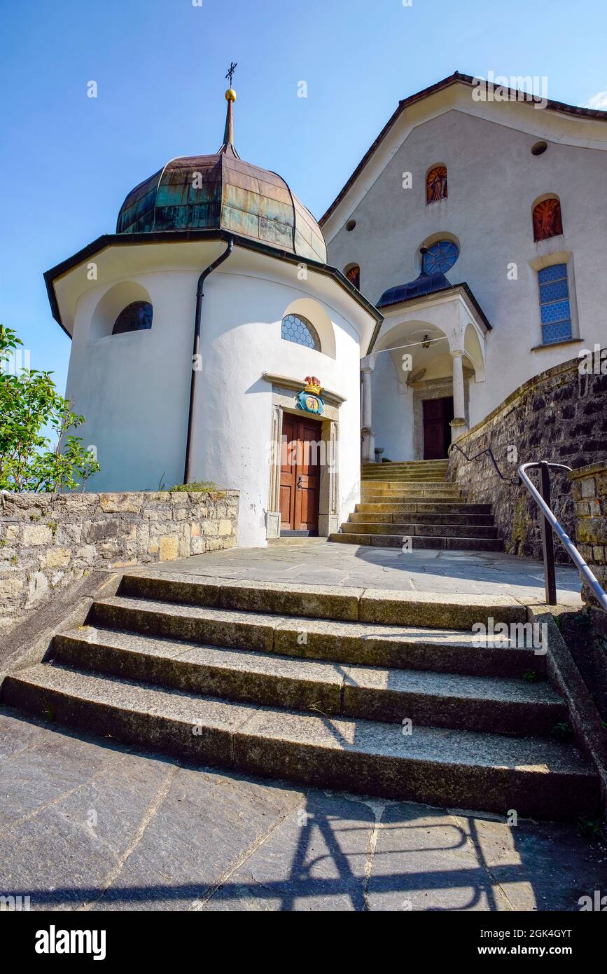 The circular cemetery chapel in front of Wassen church dates from 1742 and is crowned with an onion helmet. Wassen, Oberes Reusstal, Switzerland Stock Photo