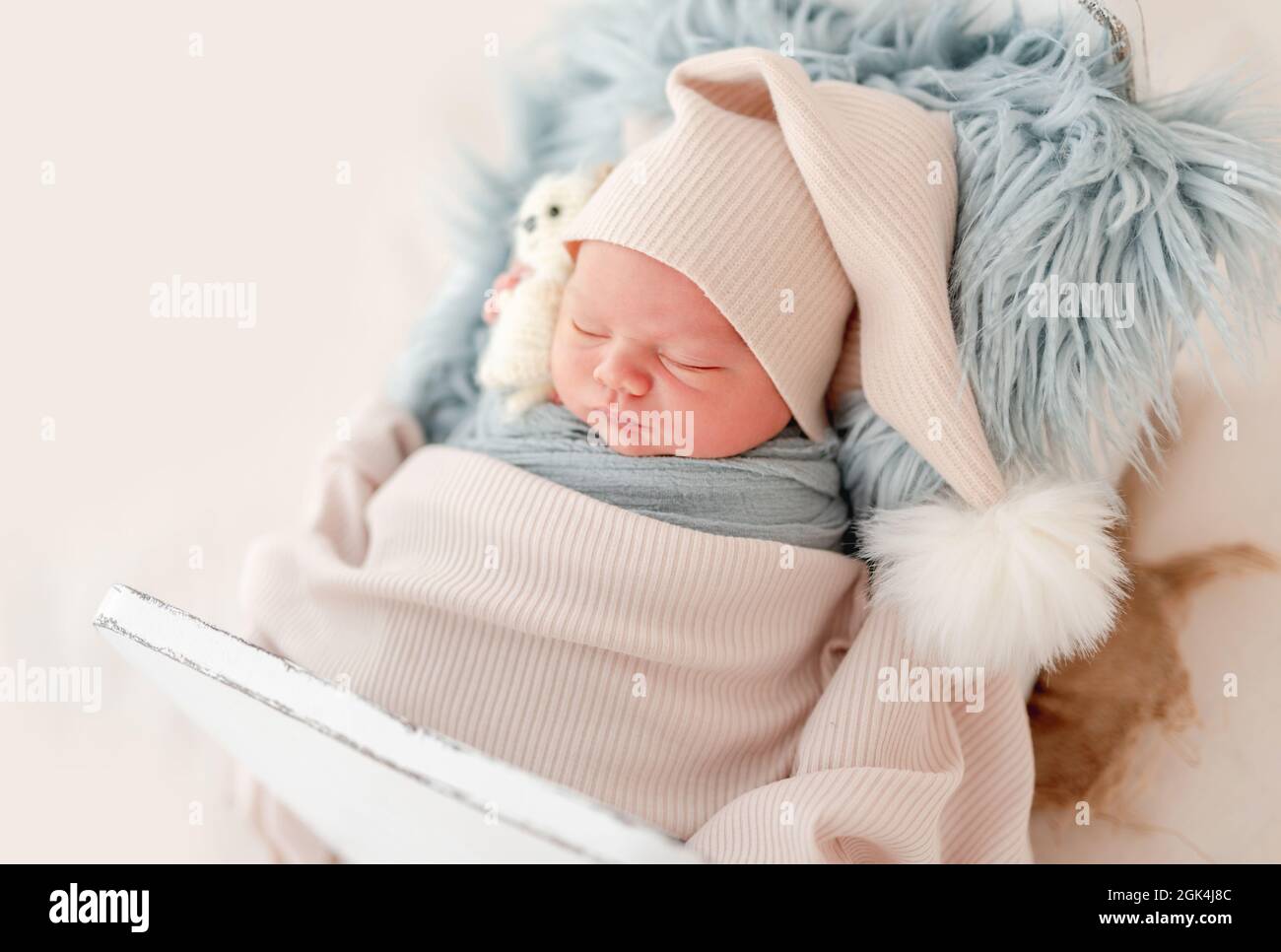 Newborn baby boy wearing knitted hat sleeping on white small designed